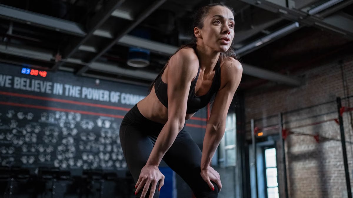 A determined female athlete takes a break during workout in an industrial-style gym.